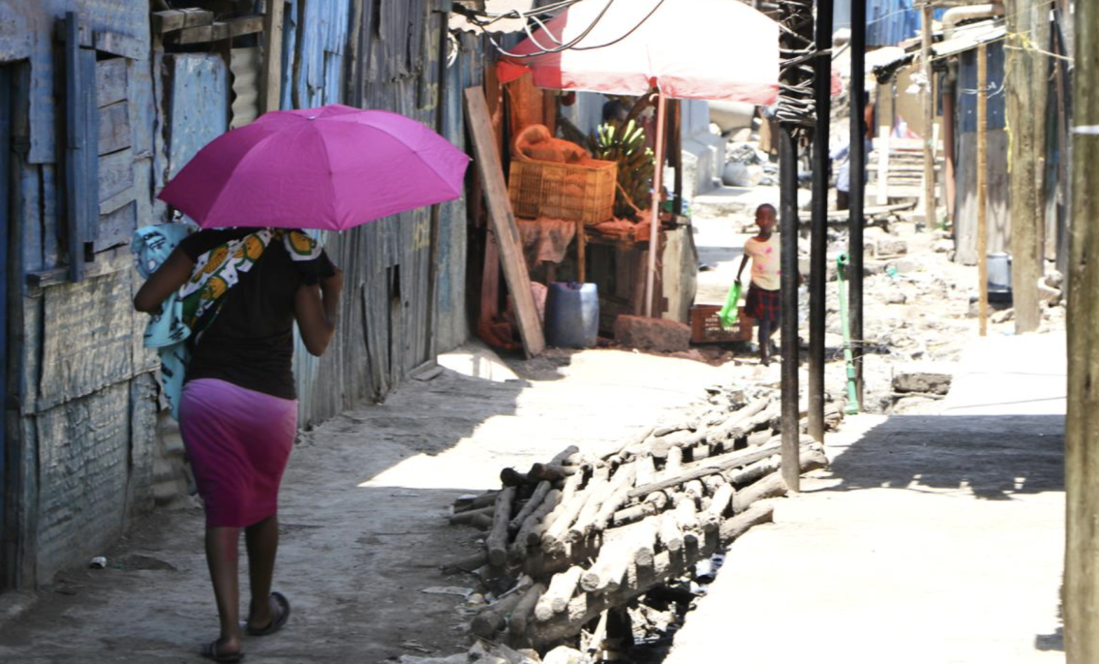 A mother walks down the street of an urban informal settlement in Nairobi, Kenya.