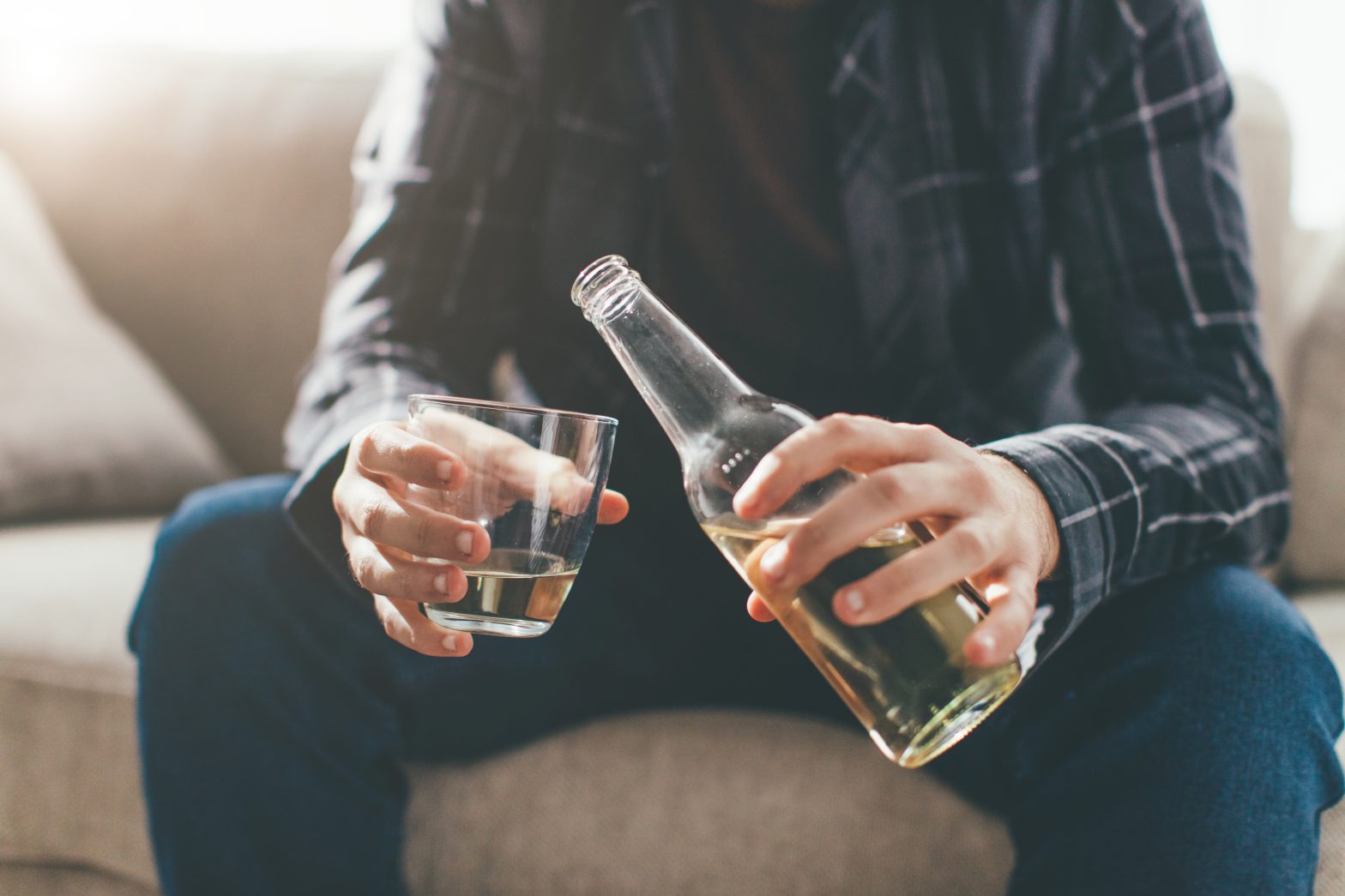 person pouring a drink from a bottle