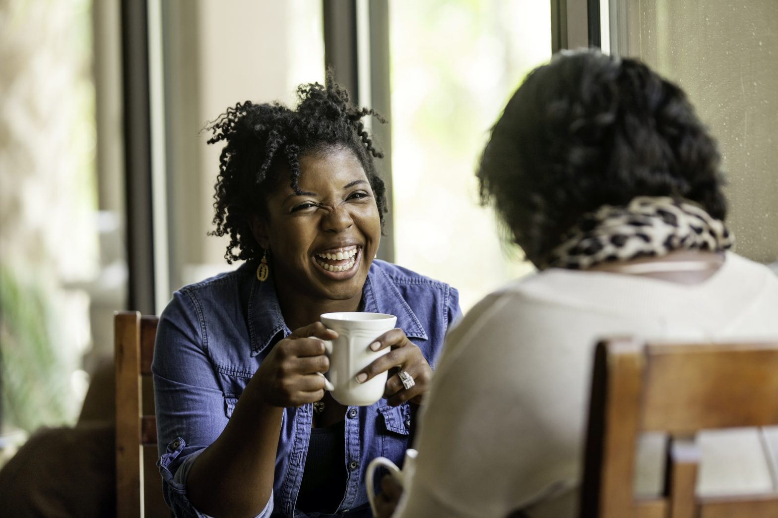 Attractive African American women have a good time with a close friend drinking good coffee.