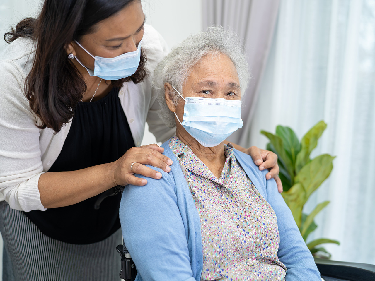 Caregiver help Asian senior or elderly old lady woman sitting on wheelchair and wearing a face mask for protect safety infection Covid-19 Coronavirus.