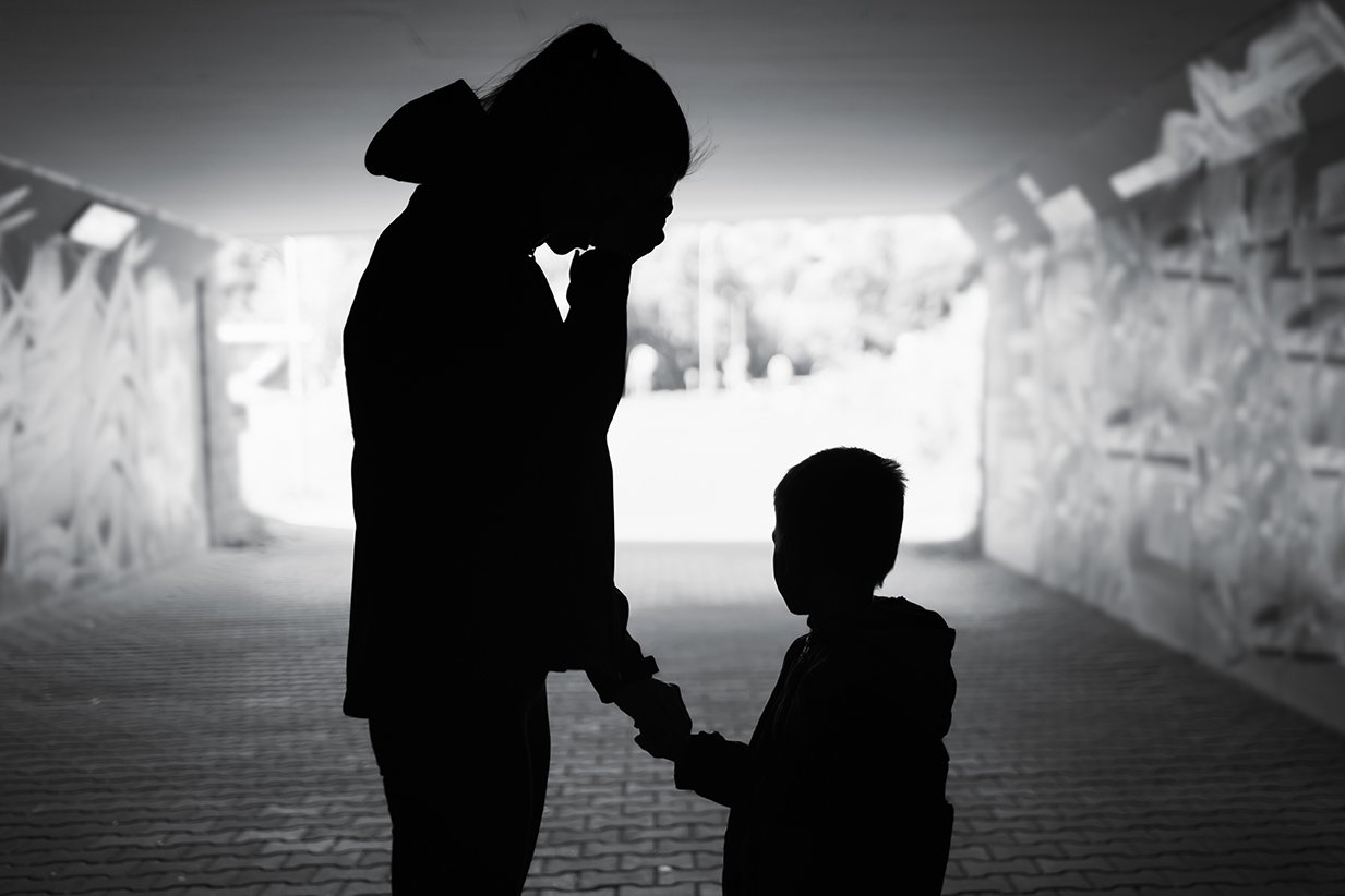 Tired sad stressed single mother and child silhouette in a tunnel with graffiti-covered walls.