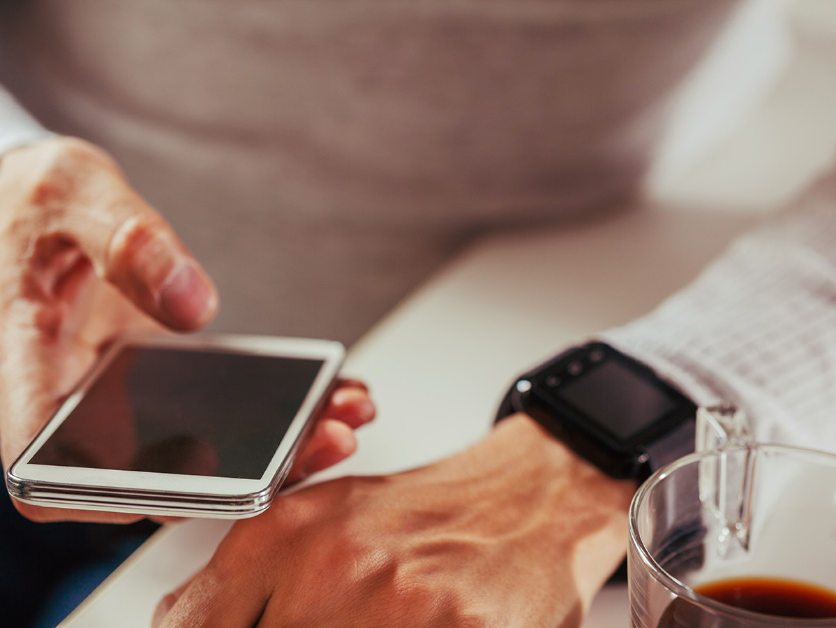 Close Up Of Male Wearing Smart Watch And Using Smart Phone.