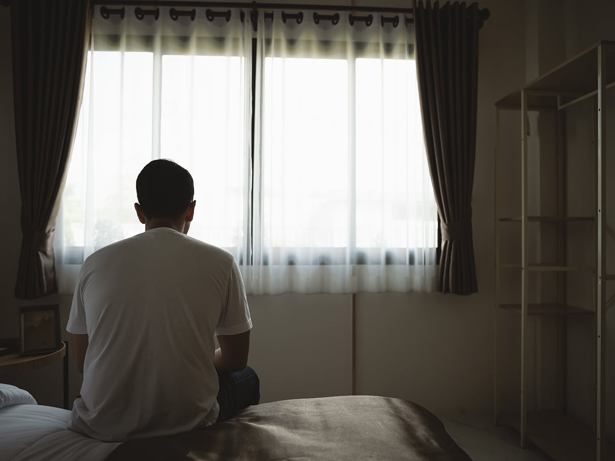 Silhouette depressed man sadly sitting on the bed in the bedroom.