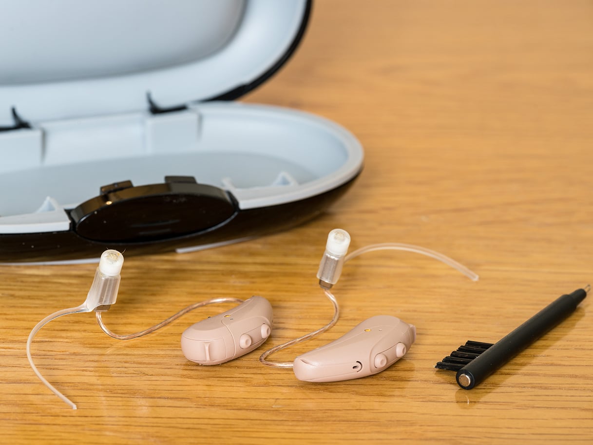 Close up of a pair of tiny modern hearing aid on bedside table