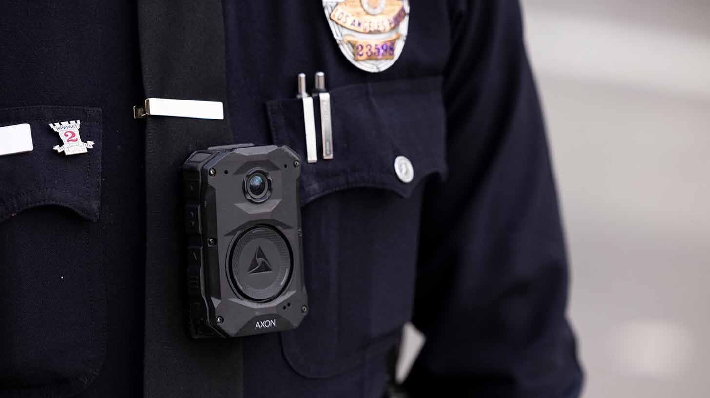 Close-up of a police officer’s uniform with a body-worn camera mounted at the center of the chest.