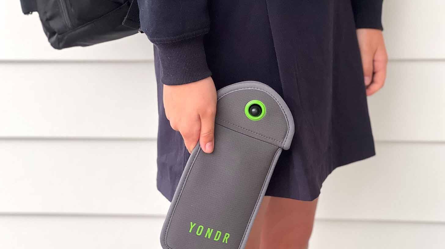 Teenager holds a lockable cell phone pouch