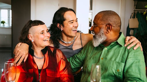 Three adults embrace and laugh together