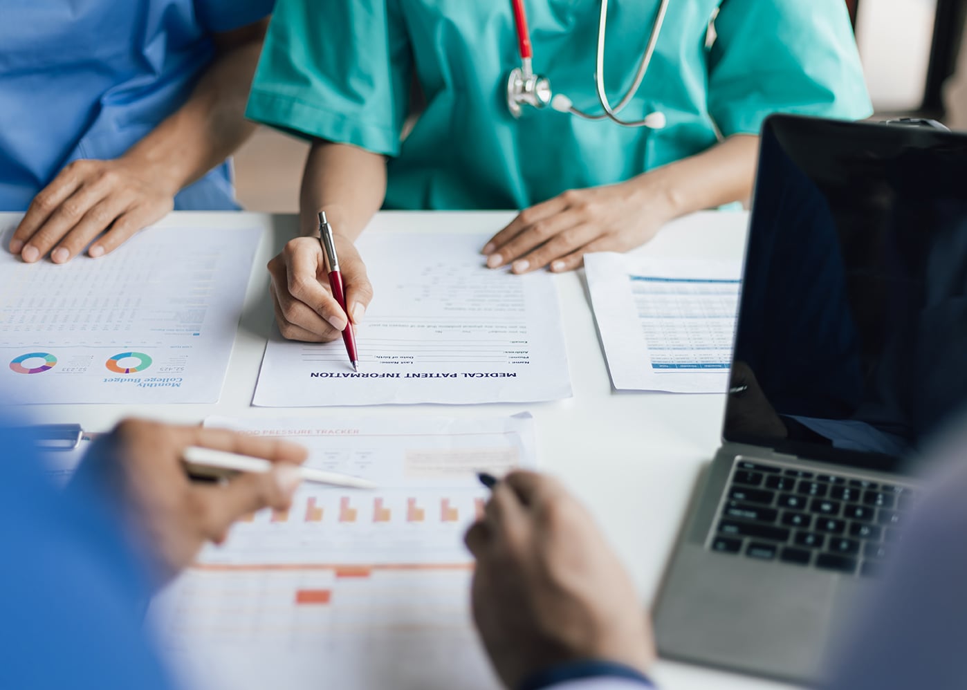 Team, medical analysts and doctors consulting with paperwork of graphs, data and charts in hospital conference room. Healthcare staff discussing statistics, results of research and innovation.